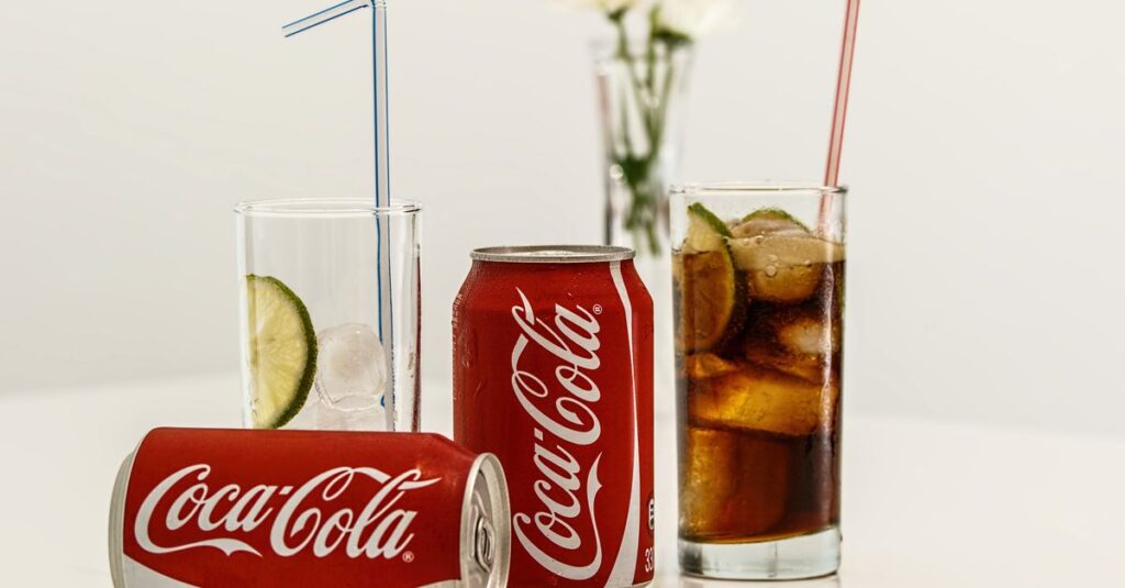 Coca-Cola cans with ice and lime on a table, fresh and invigorating.